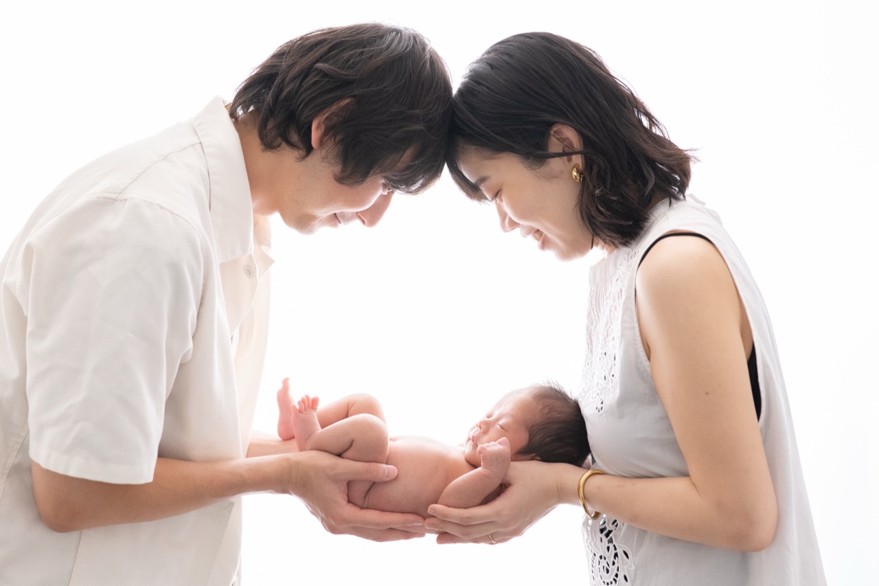 パパとママの手に抱かれた赤ちゃんの家族写真
